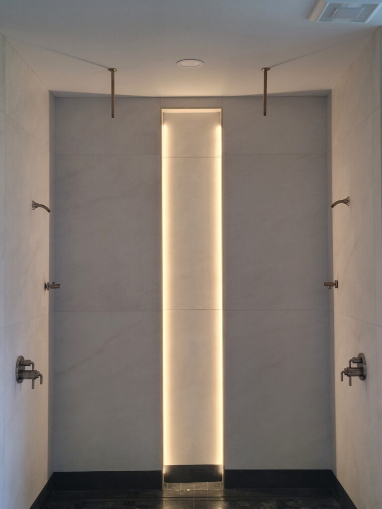 Walk-in shower with a lit vertical niche, part of a Houston bathroom remodel lighting project