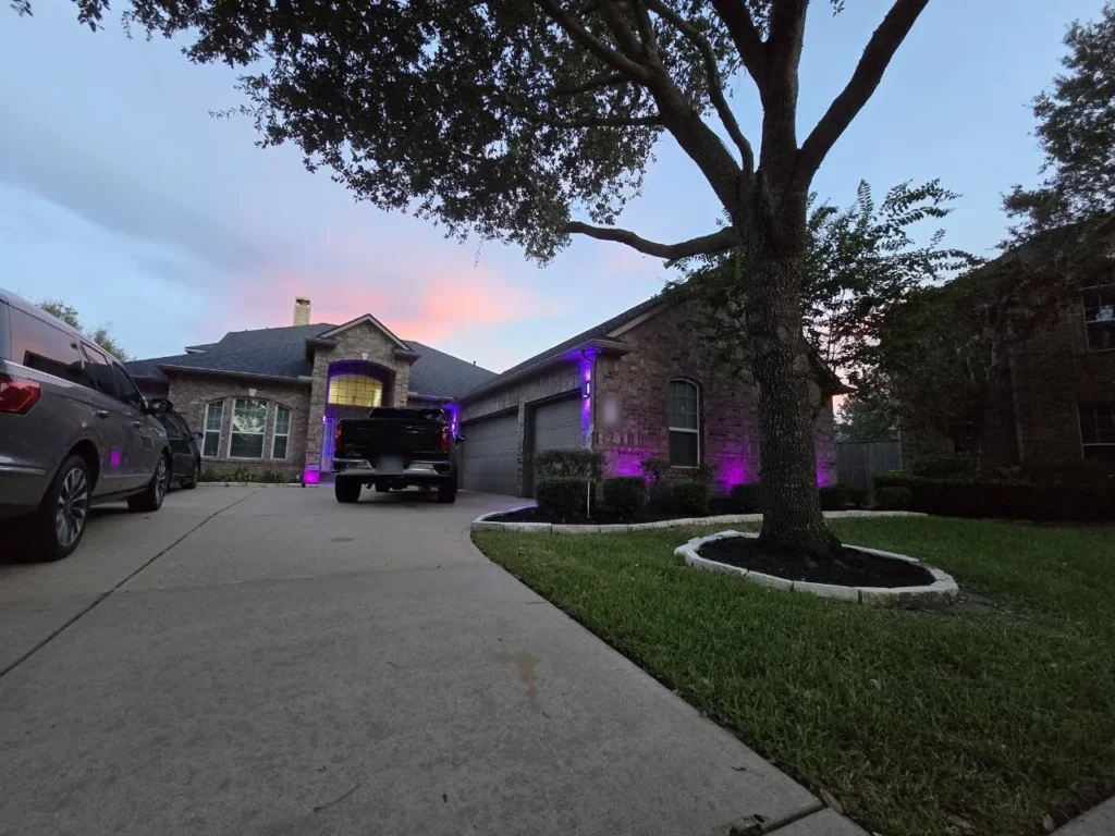 Purple Landscape Lighting at Sunset – Houston - Laymance Lighting Wide view of a Houston home at sunset with purple color-changing landscape lighting on the facade and a large live oak in front, by Laymance Lighting